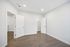 Bright modern bedroom with sleek hardwood floors, crisp white walls, and multiple doorways, offering ample space and functionality.