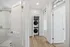 Bright apartment hallway with elegant stained glass, highlighting a modern bathroom and in-unit stacked washer-dryer.