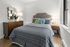Chic and cozy bedroom with stylish gray bedding, elegant wooden furniture, and large windows inviting natural light.