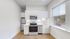 Bright and modern kitchen featuring sleek stainless steel appliances, white cabinetry, and natural light from a large window.