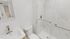 Elegant bathroom with a sleek white vanity, modern faucet, and a glass-enclosed shower featuring stylish marble tiles.