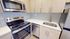 Modern kitchen with sleek stainless steel appliances, herringbone tile backsplash, and light wood cabinetry.