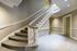 Elegant curved staircase with white balusters and carpeted steps in a well-lit hallway with classic architectural details.