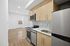 Modern kitchen with sleek stainless steel appliances, chic backsplash, and wood cabinetry, leading to a bright open living space.