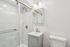 Modern bathroom featuring sleek marble tile shower, elegant vanity, and contemporary lighting.