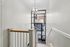 Bright and welcoming staircase entrance with modern chandelier and large window offering street views.