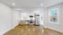 Bright, modern kitchen with stainless steel appliances, sleek white cabinetry, and elegant hardwood floors, featuring large windows for natural light.