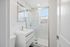 Modern bathroom featuring sleek white fixtures, a glass shower with marble-style tiles, and a large mirror.