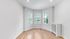 Bright and inviting room with large windows, elegant hardwood floors, and a serene view of lush greenery.