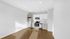 Elegant modern kitchen with sleek white cabinets, stainless steel appliances, and rich hardwood floors basking in natural light.