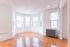 Bright and inviting apartment corner with elegant parquet flooring and large bay windows offering abundant natural light.