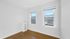 Bright and airy room with elegant hardwood floors and large windows offering a stunning city view.