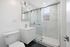 Modern bathroom with elegant marble tiles, sleek white vanity, and a stylish glass shower enclosure.