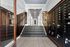 Chic apartment entrance with elegant patterned flooring, sleek wooden stairs, and modern mailboxes, creating a welcoming ambiance.