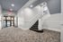 Elegant apartment lobby with modern carpeting and a stylish staircase leading to upper floors, creating a welcoming entrance.