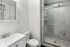Elegant bathroom featuring a sleek glass-enclosed shower, modern vanity, and clean white finishes.