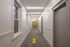 Bright, modern hallway with sleek gray doors and accent lighting, featuring stylish patterned carpet and frosted windows.