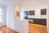 Bright and modern kitchen with sleek dark wood cabinets, stainless steel appliances, and warm hardwood flooring, ideal for culinary enthusiasts.