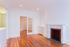 Bright living room with elegant hardwood floors, a charming fireplace, and French doors inviting natural light.