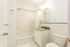 Elegant bathroom with a modern granite-topped vanity, bathtub, and bright lighting.