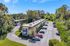 Aerial view of a charming apartment complex surrounded by lush greenery and ample parking.