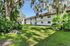 Charming two-story apartment building surrounded by lush greenery and mature trees.