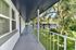 Charming apartment walkway overlooking lush greenery and neighboring buildings.