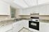 Bright, modern kitchen with sleek white cabinets, granite countertops, and stainless steel sink.