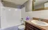 Bright and inviting bathroom with a modern vanity, large mirror, and cozy bathtub.