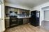 Modern kitchen with sleek dark cabinets, a black stove and refrigerator, and wood flooring.
