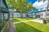 Sunny courtyard of a modern apartment complex with lush greenery and a central seating area.
