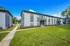 Sunny view of a modern apartment complex with manicured lawns and path.