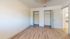 Bright and airy bedroom featuring wood flooring and dual closets with open doors.