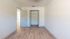 Spacious bedroom with open closet, modern flooring, and natural light.