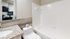 Modern bathroom featuring sleek granite countertops, elegant white tiles, and a pristine bathtub for a luxurious touch.