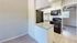 Chic kitchen with modern appliances, sleek black and white design, granite countertops, and light wood flooring.