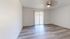 Bright and airy living space with modern wood flooring and a ceiling fan next to sliding glass doors leading to a serene outdoor view.