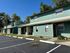 Charming green townhouse complex with ample parking space and serene natural surroundings under a clear blue sky.