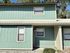Charming two-story townhouse with a fresh mint green exterior and crisp white trim nestled amidst lush greenery.