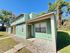 Charming two-story townhouse with mint green siding, nestled in a serene, green landscape under a bright blue sky.