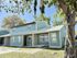 Charming two-story blue-green home with a metal roof, nestled among lush trees in a serene neighborhood setting.