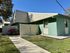 Charming single-story apartment with teal siding, modern metal roofing, and a welcoming landscaped front yard.