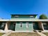 Charming duplex with green exterior, modern design, and well-maintained landscaping under a clear blue sky.