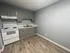 Elegant kitchen space featuring modern gray cabinets, sleek white appliances, and stylish wood flooring.