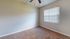 Bright and inviting bedroom with plush carpet and a large window, perfect for natural light and relaxation.