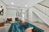 Contemporary living room with elegant staircase, vibrant decor, and an open view to the sleek kitchen.