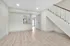 Modern open-concept living space featuring sleek staircase, elegant light wood flooring