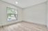 Bright and airy room featuring sleek hardwood flooring, large windows offering a serene view of lush greenery outside.