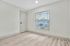 Bright and modern bedroom with sleek flooring, ample natural light, and a view of the charming neighborhood from the window.
