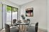 Bright dining area with elegant four-seater table, artistic wall decor, and garden view through large sliding doors.